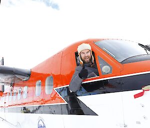 A man leans out the window of a plane.