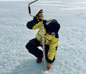 A man uses a drill to test the ice thickness.