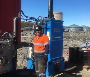 A man stands beside a drum crushing machine