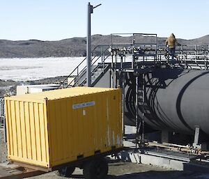 A man standing on top of a fuel farm tank