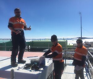 Three tradesmen repair a roof.