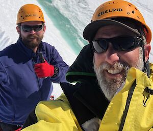 Two men pose above an ice cliff