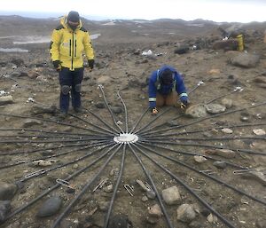 two men install cables on the ground