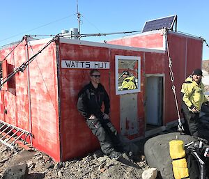 Two men outside a hut