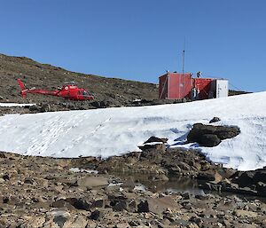 A helicopter parked beside a hut