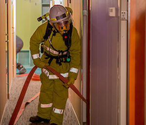 A fire team member assisting with the fire hose as they conduct a search of the orange door dongas.