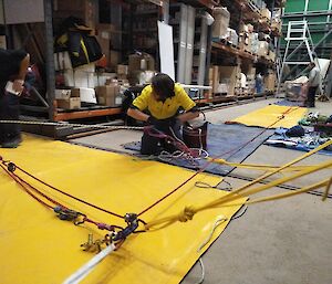 Person kneeling and passing rope through his hands in simulation stretcher raise.