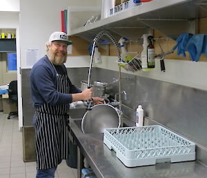 Terry standing at the kitchen sink washing the large stainless steel mixing bowl.