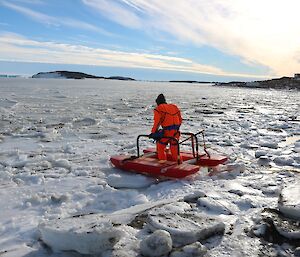 Expeditioner in bright orange dry suit taking the first steps onto the se ice utilising the rescue alive unit.