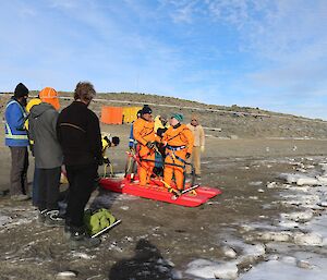 Two expeditioners in bright orange dry suits getting ready to head out onto the ice but not before one last joke.