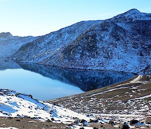 Photo of the sandy Club Lake beach with a reflection of the surrounding hills in the mirror finish still water.