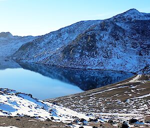 Photo of the sandy Club Lake beach with a reflection of the surrounding hills in the mirror finish still water.