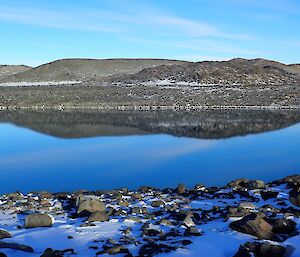 View looking across the lake with reflections on the surrounding hills in the still waters.