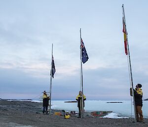 One expeditioner at each of the three flagpoles to the raise the flags.
