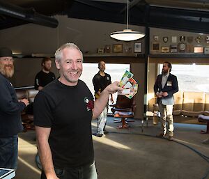 Expeditioner holding up his fake money that he has won playing two up with the rest of the group playing another round behind him.