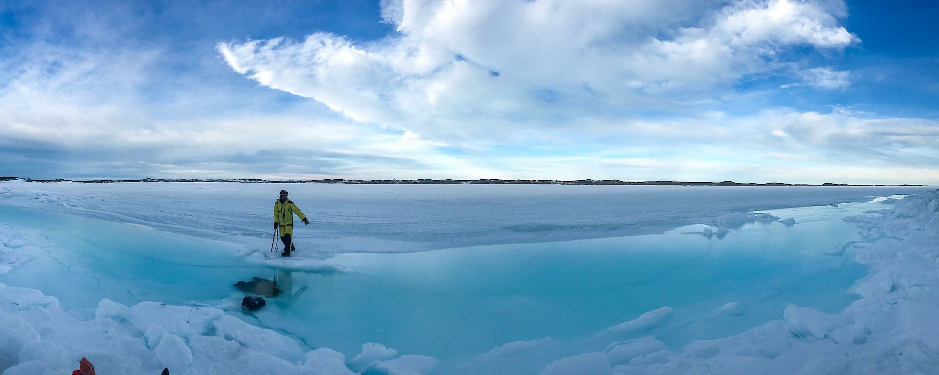 shallow moat of blue water between the island and formed in the sea ice at the tide line.