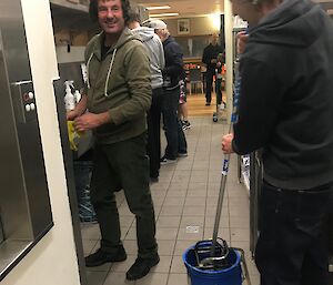 A group of expeditioner all jump in to help the slushy after the evening meal to wash the dishes and mop the floor.