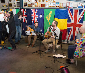 The band set up in front of the wall covered with flags.