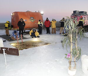 Looking at the swim location with fake trees and swim hole in the foreground and expeditioners, red RMIT van and pink Hagg in the background