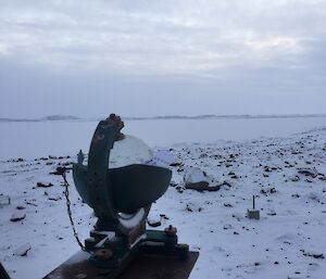 Snow covered rocks and ice with cloudy sky and a sunshine recording instrument.