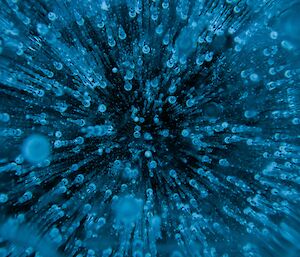 Close up photo of small air bubbles trapped in the frozen fresh water lake.