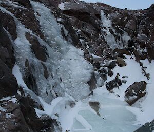 Frozen summer stream as it cascades over the edge of the gorge.