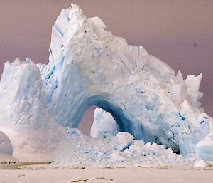 Pyramid shaped ice berg with a large hole trapped in the sea ice.