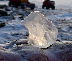 A small piece of ice on a rock that is covered with very fine frost particles.