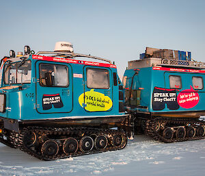 The brightly coloured blue Hägglunds vehicle parked on the snow covered sea ice.
