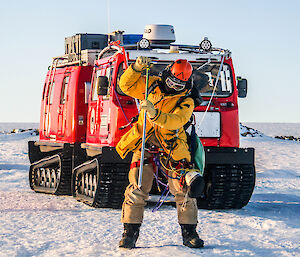 Expeditioner roped up in front of the red Hagglund vehicle probing the snow.