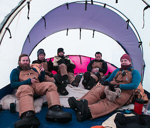 Chris, Derryn, Simon, Richard and Kate reclining on sheepskin rugs in one end of the Endurance tent, with hot drinks.