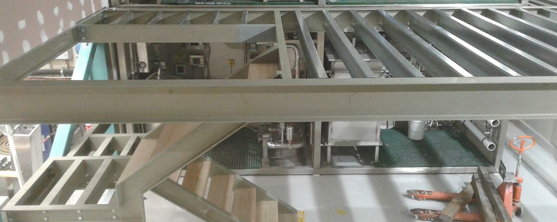The first floor steel and stair structure installed in front of the waste treatment units, ready for the floor sheeting.