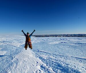 Woman jumping for joy in icy landscape
