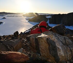 Expeditioner sitting down on a high rocky outcrop looking over the Rauer Islands