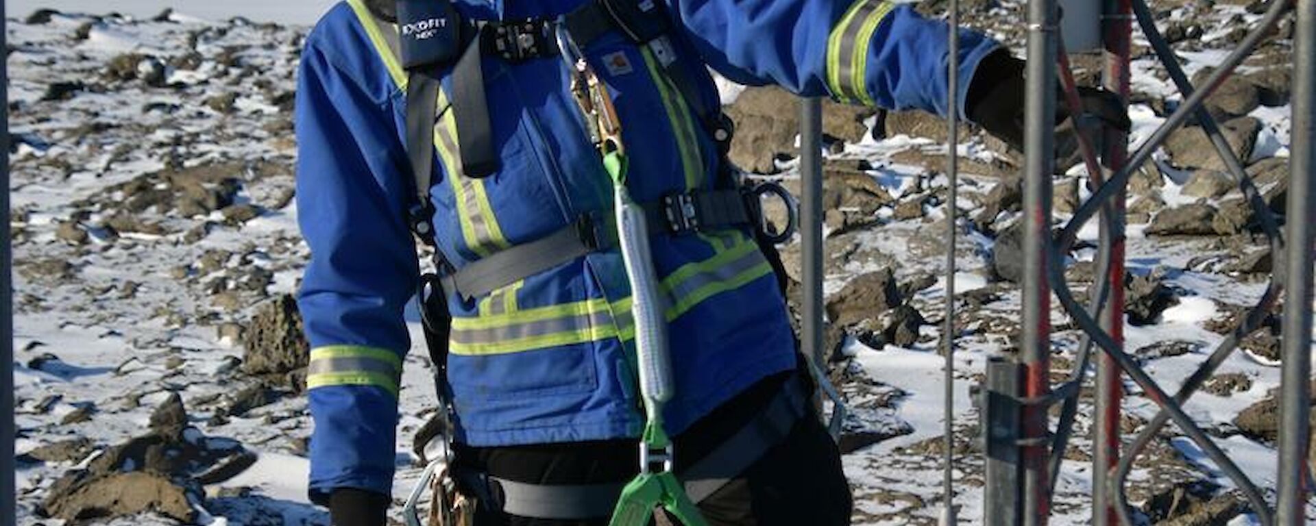 Expeditioner wearing climbing harness at the base of the mast and looking up to the top