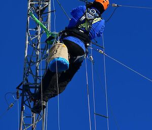 Expeditioner leaning back making the repair at the top of the mast