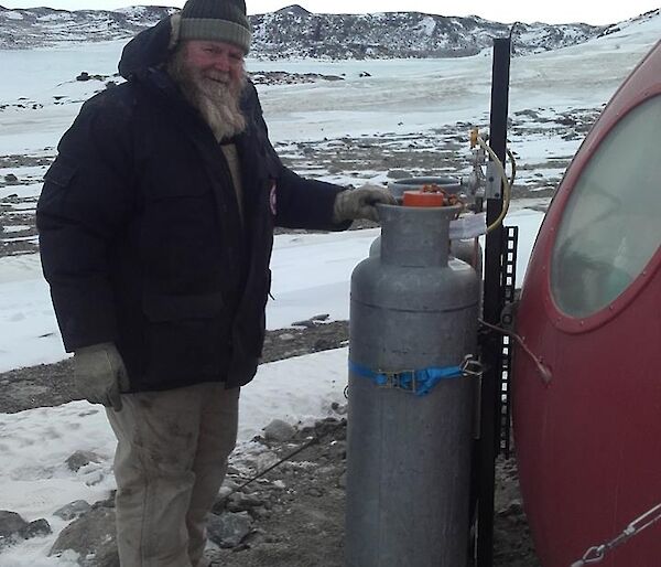Glenn standing next to the newly installed gas system on the side of the Apple hut.