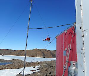 A red squirrel helicopter flying over the frozen fjord as it comes into land at Watts Hut.