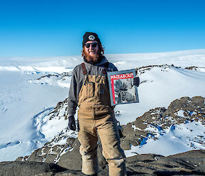 Expeditioner at Wikins Cairn holding up Walkabout Magazine