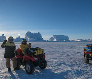 two expeditioners on the sea ice, one standing one sitting on a quad bike