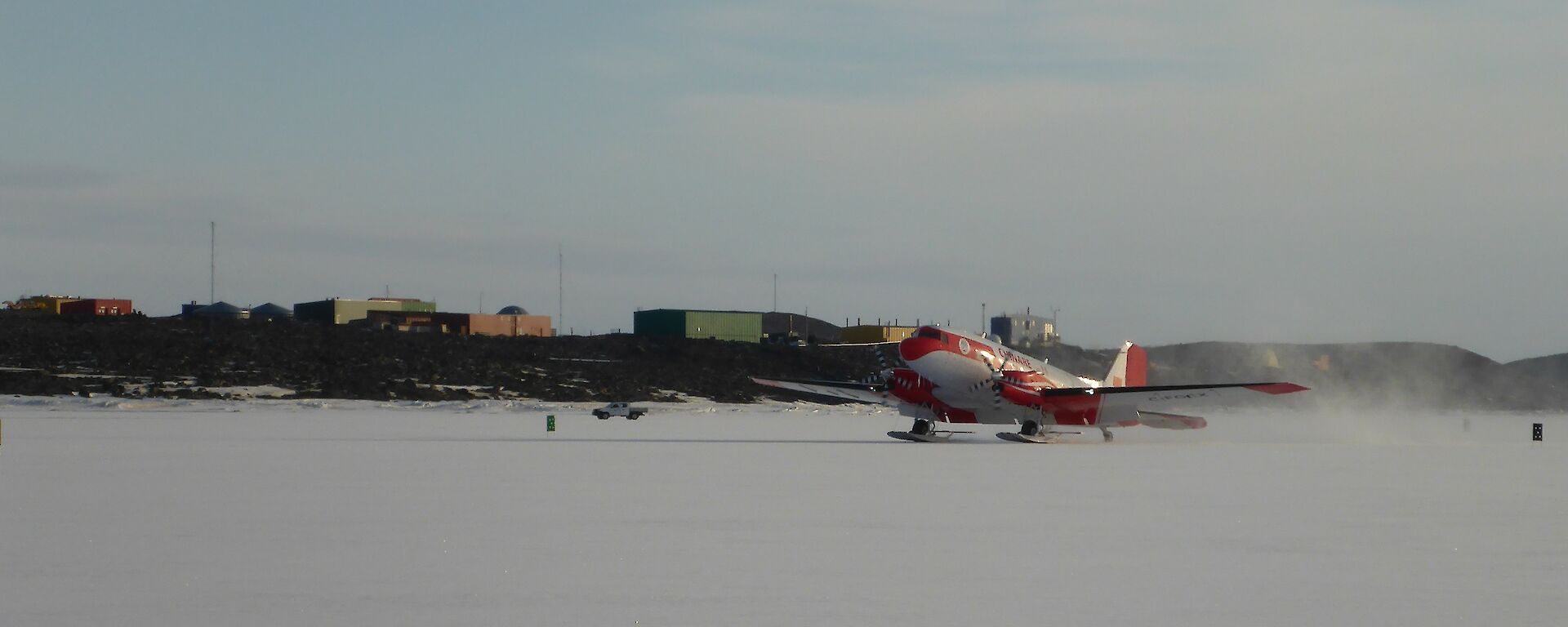 The Basler DC 3 landing on the sea ice with Davis station in the background.