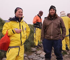 Expeditioners stand outside at Macquarie Island, one ready to depart to a tourist ship off shore