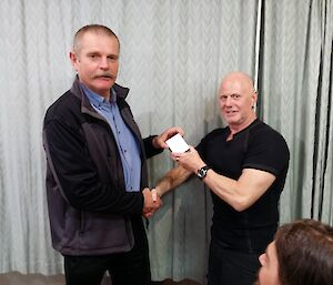 Station leader Ivor presents Graeme with his Antarctic winterer’s medallion