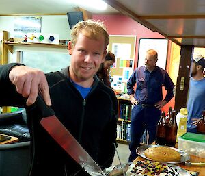 Expeditioner cuts cake with large knife