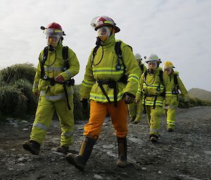 Two male expeditioners lead a team of people all dressed in firefighting gear outside on Macquarie Island
