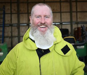 Older, bearded male expeditioner smiles at camera while wearing firefighting clothing