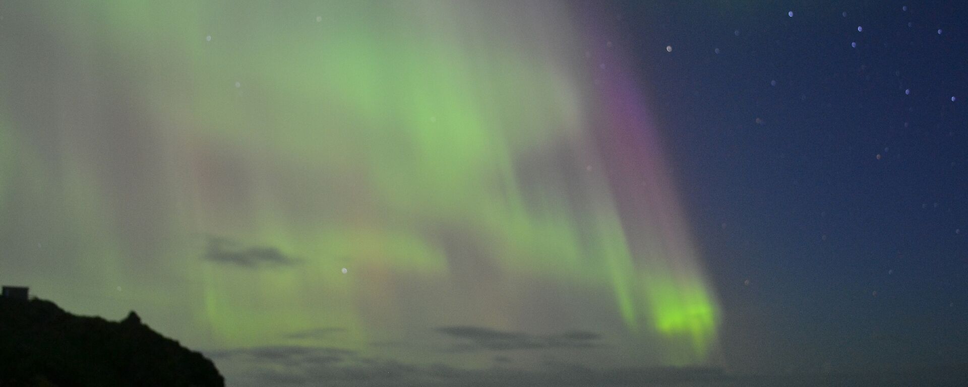 The light of an aurora dances just off shore at Macca