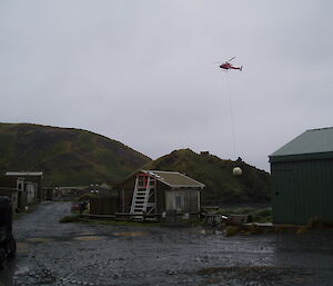 Helicopter sling loading a water tank over station