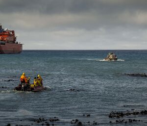 Looking out to sea from shore with ship Aurora Austrails in background, and an amphibious vehicle and two inflatable boats in foreground