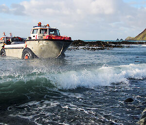 An amphibious vehicle drives out of the water onto the beach